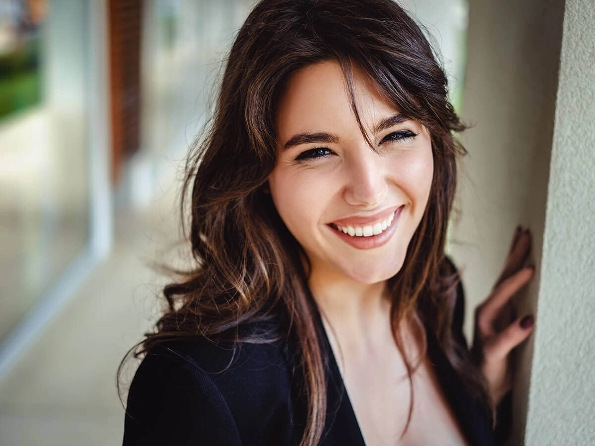 Smiling woman showcasing results of dental bonding and contouring